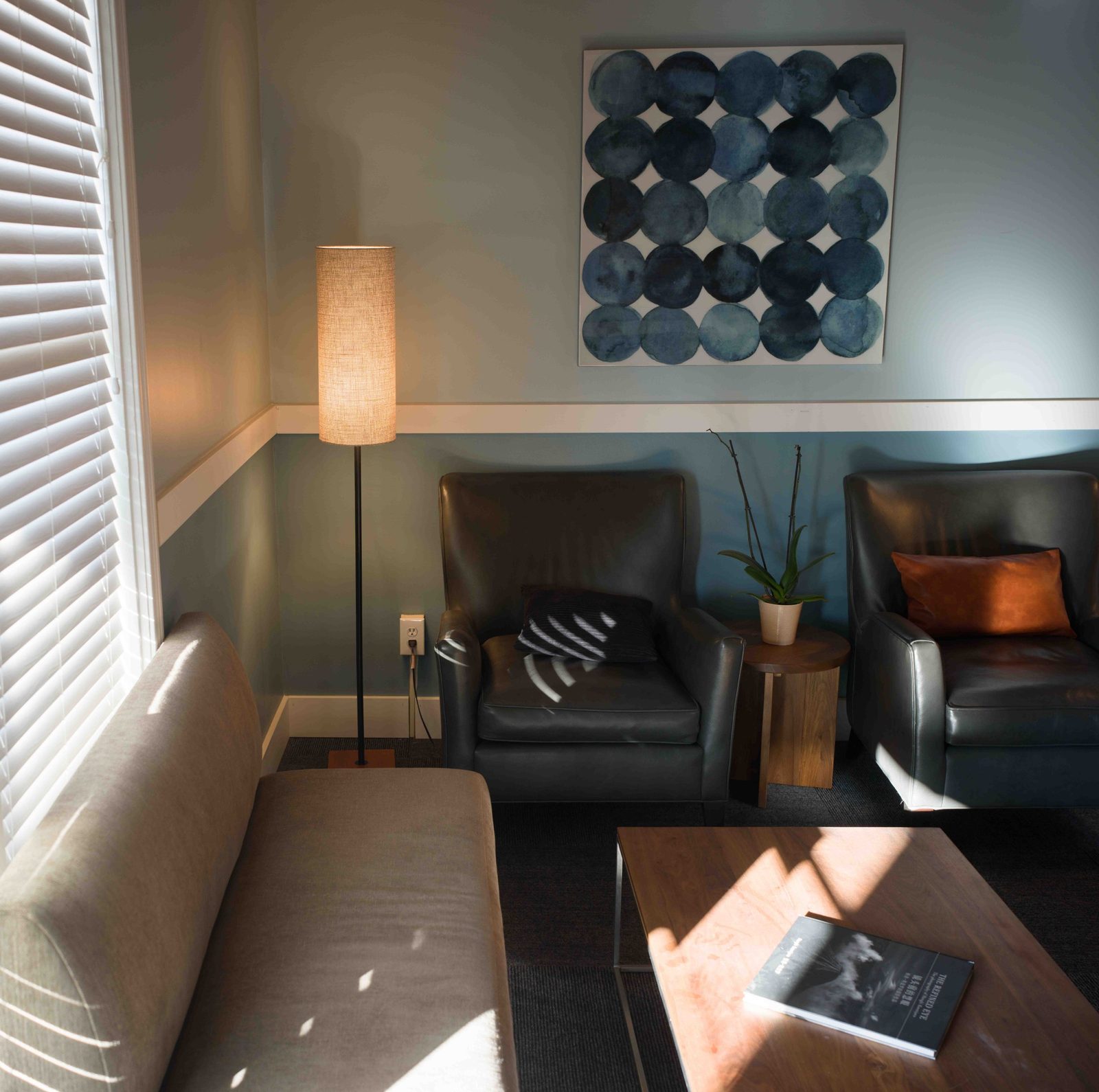 The Sound Injury waiting room in Edmonds: a sofa and two leather armchairs, a floor lamp, and afternoon light coming through the blinds
