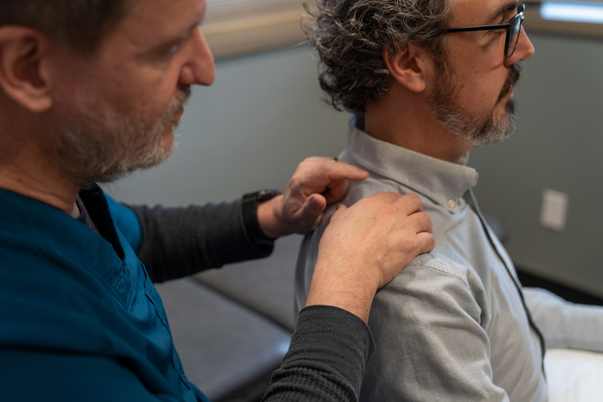 Dr. Franke examining a patient's neck and shoulder, both men in profile